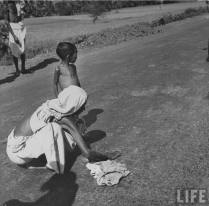 A womans collects fallen grains of food from the road. (Picture by life.com; courtesy - oldindianphotos.blogspot.com.). Click for larger image